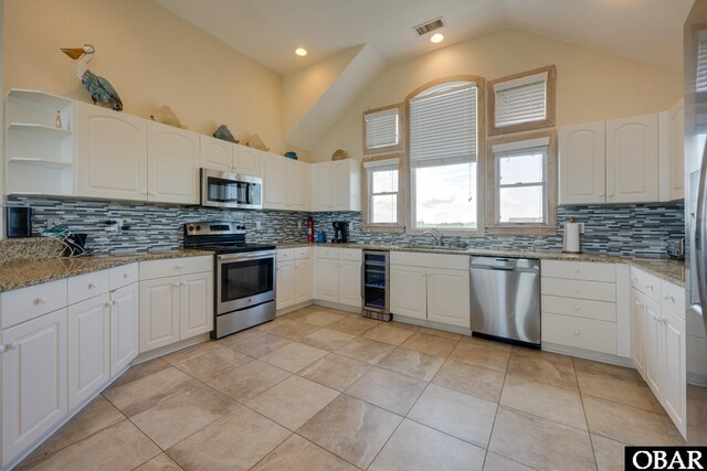 kitchen with light stone countertops, appliances with stainless steel finishes, white cabinets, and a sink