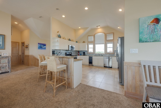 kitchen featuring wine cooler, a breakfast bar, open shelves, appliances with stainless steel finishes, and light carpet