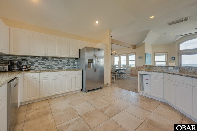 kitchen featuring stainless steel appliances, visible vents, white cabinetry, vaulted ceiling, and light stone countertops