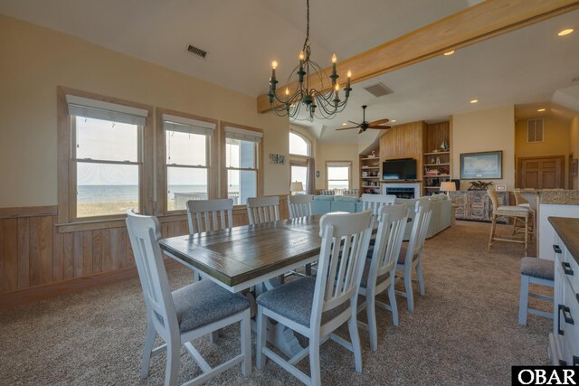 dining space with light carpet, visible vents, wainscoting, lofted ceiling with beams, and a water view