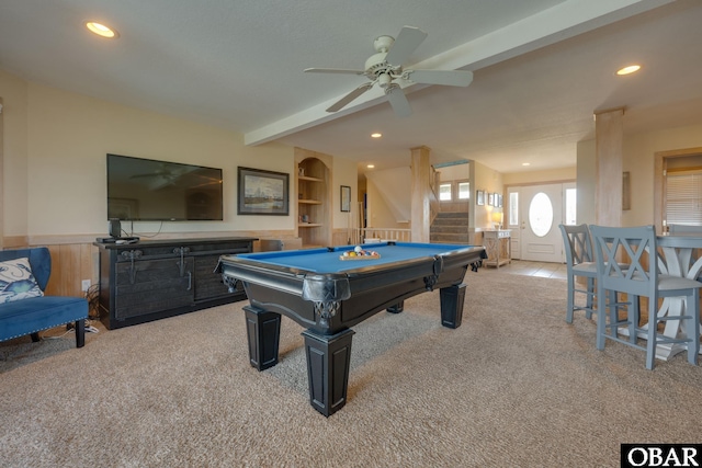 recreation room with a wainscoted wall, built in shelves, light carpet, and beam ceiling