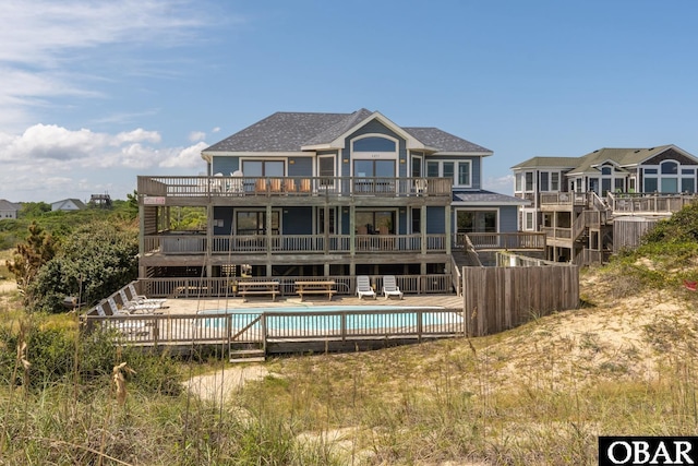 rear view of property with a balcony, a wooden deck, and a community pool