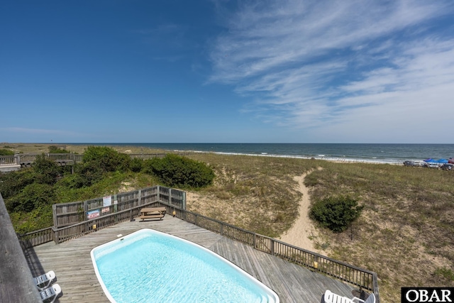 view of swimming pool featuring a fenced in pool, a view of the beach, and a deck with water view