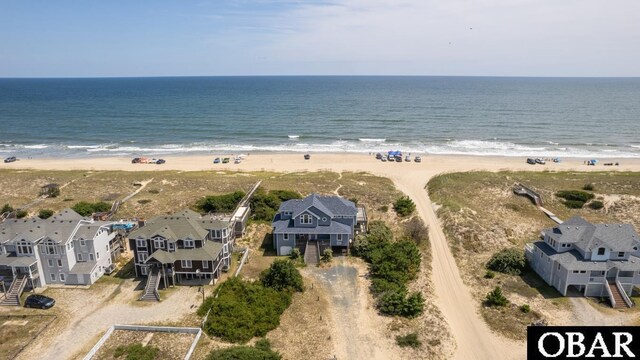 drone / aerial view featuring a water view, a residential view, and a beach view