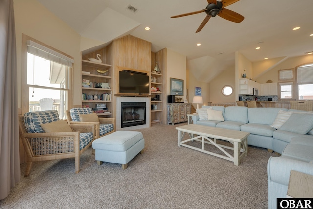 living area with built in shelves, lofted ceiling, visible vents, and a fireplace