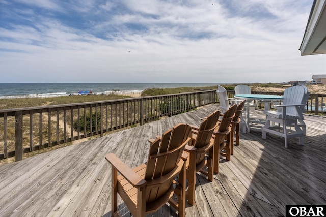 wooden deck with outdoor dining space, a water view, and a beach view