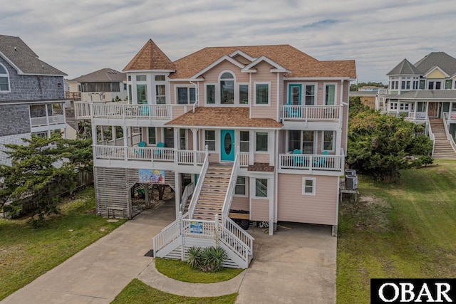 view of front of home featuring driveway, a balcony, stairway, roof with shingles, and a carport