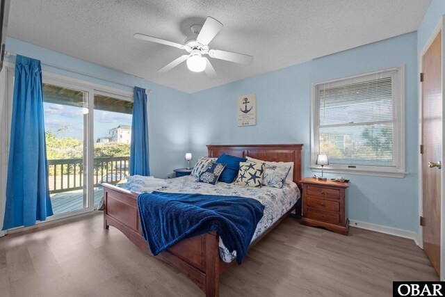 bedroom featuring a textured ceiling, multiple windows, light wood-style flooring, and access to exterior