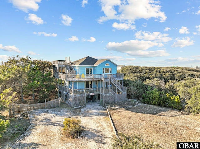 view of front facade featuring driveway, stairs, fence, and a wooden deck