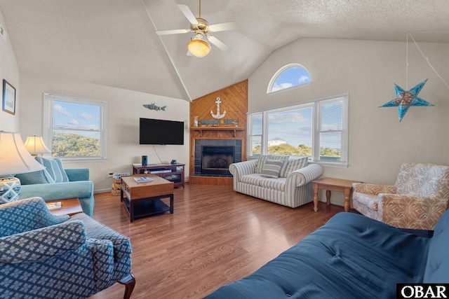 living area with dark wood-style flooring, ceiling fan, a textured ceiling, high vaulted ceiling, and a tile fireplace