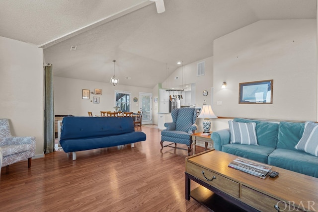 living area with high vaulted ceiling, wood finished floors, and visible vents