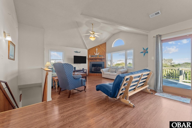 living area with a wealth of natural light, a fireplace, visible vents, and wood finished floors