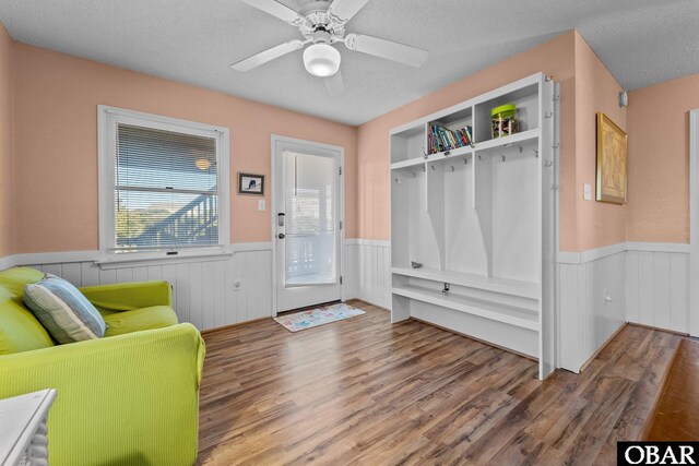 interior space featuring a wainscoted wall, ceiling fan, a textured ceiling, and wood finished floors