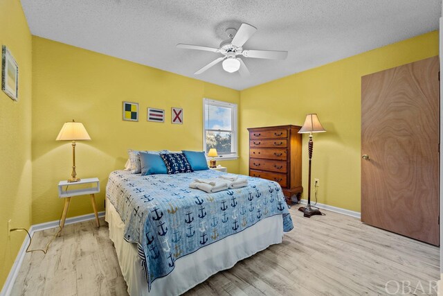 bedroom featuring light wood-style flooring, baseboards, ceiling fan, and a textured ceiling