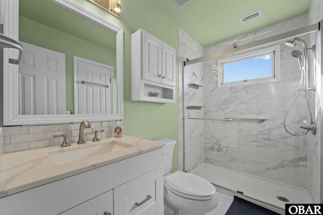 bathroom featuring a marble finish shower, visible vents, vanity, and toilet