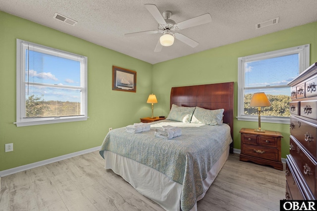 bedroom with light wood-style flooring, visible vents, and baseboards