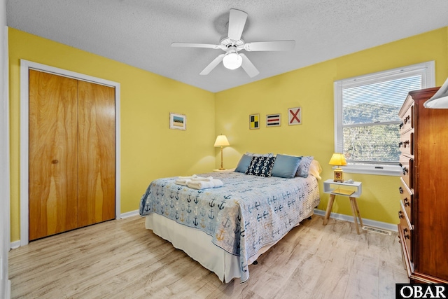 bedroom with a textured ceiling, light wood finished floors, a ceiling fan, and baseboards