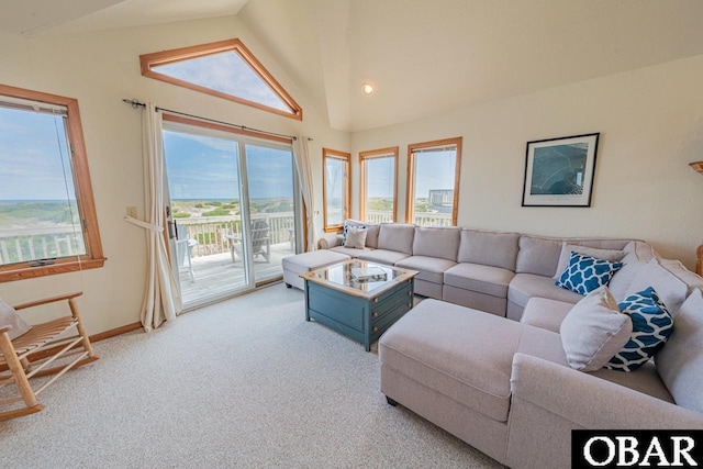 carpeted living area with baseboards and high vaulted ceiling