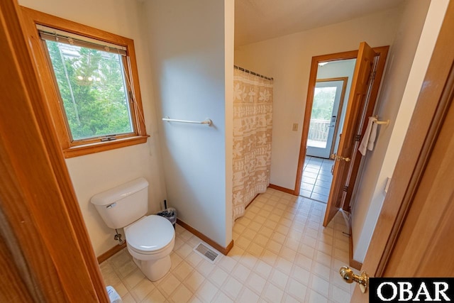 full bath featuring toilet, a shower with curtain, visible vents, and baseboards