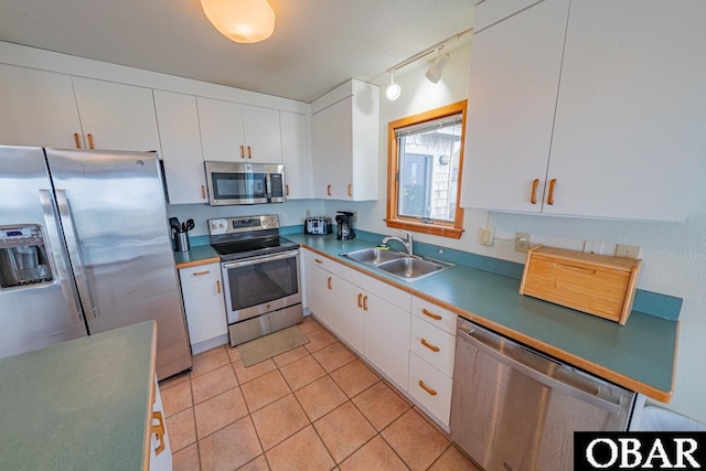 kitchen featuring stainless steel appliances, a sink, white cabinetry, track lighting, and light tile patterned floors