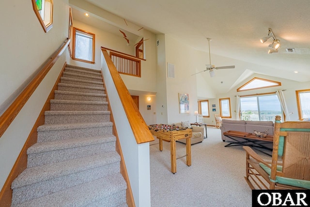 stairway with vaulted ceiling, a ceiling fan, carpet flooring, and visible vents