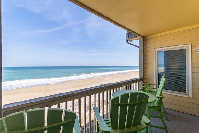 balcony with a view of the beach, a sunroom, and a water view