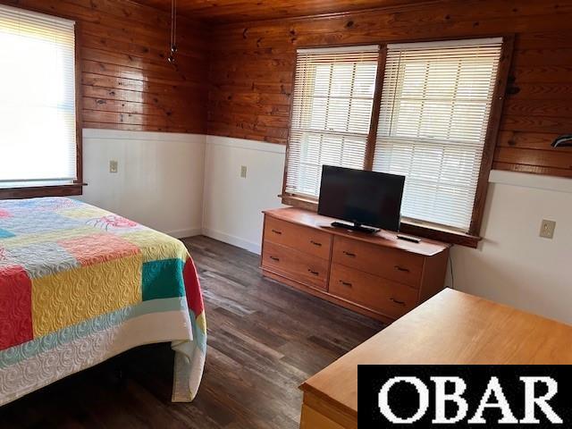 690 Irvin Garrish Hwy Lot # 2A, Ocracoke, NC 27960 - bedroom featuring multiple windows, wooden walls, and dark wood finished floors