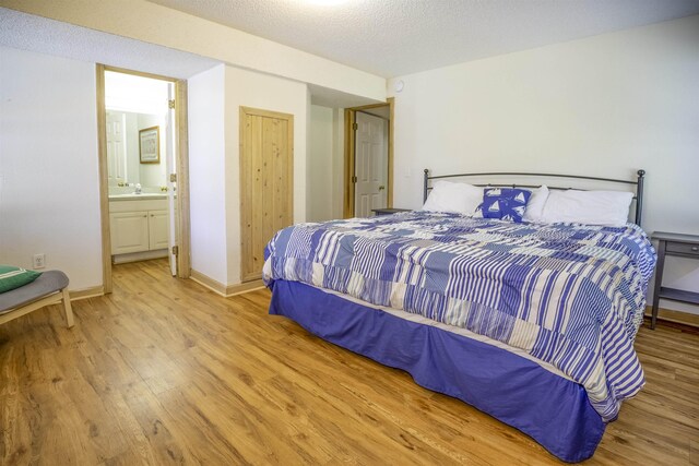 bedroom featuring a sink, a textured ceiling, baseboards, and wood finished floors