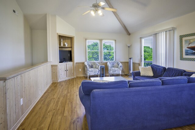 living area featuring built in shelves, a wainscoted wall, and light wood-style floors