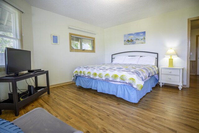 bedroom featuring a textured ceiling, baseboards, and wood finished floors