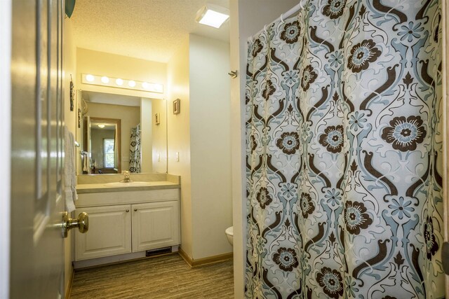 full bathroom featuring baseboards, toilet, wood finished floors, a textured ceiling, and vanity