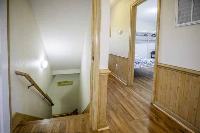 staircase with wood walls, wainscoting, and wood finished floors