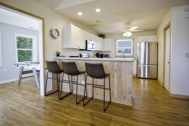 kitchen featuring light countertops, appliances with stainless steel finishes, a peninsula, and white cabinets