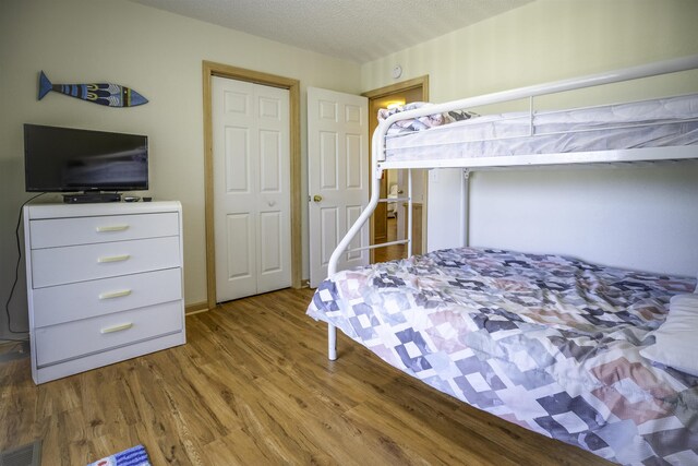 bedroom with light wood finished floors, visible vents, and a textured ceiling