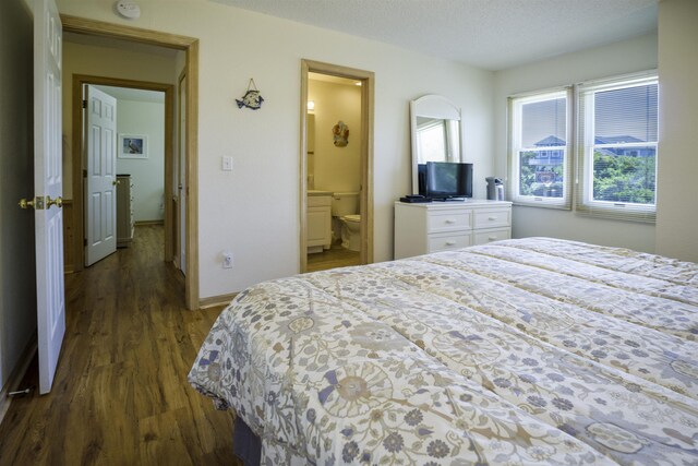 bedroom with dark wood-style floors, baseboards, a textured ceiling, and ensuite bathroom