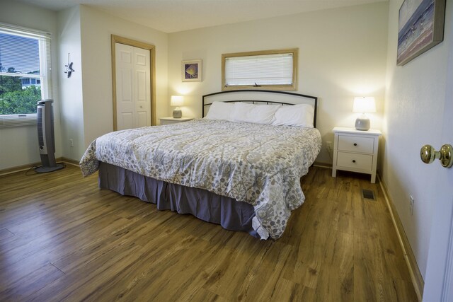 bedroom with a closet, visible vents, baseboards, and wood finished floors