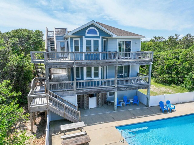 back of property featuring stairs, a deck, a patio area, and a fenced in pool