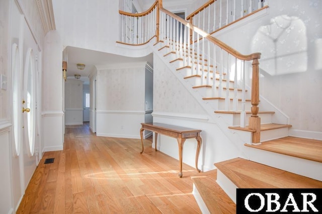 stairs featuring visible vents, a towering ceiling, baseboards, and wood finished floors