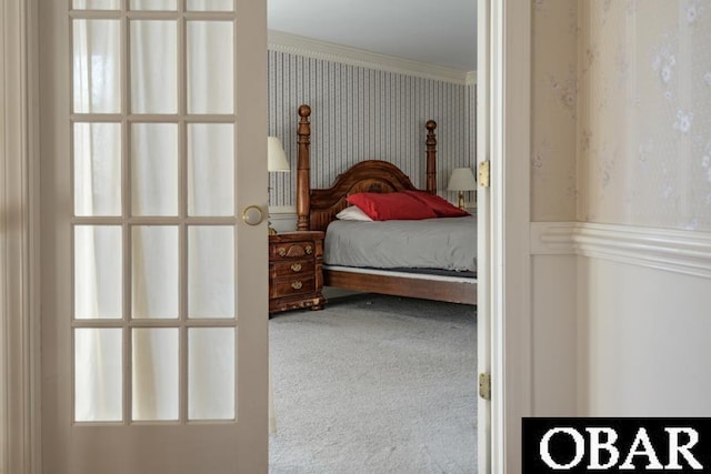 carpeted bedroom with crown molding and wallpapered walls