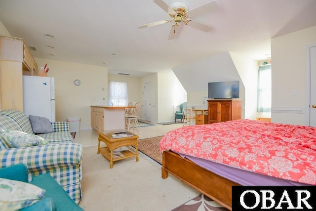 bedroom featuring ceiling fan, multiple windows, and freestanding refrigerator