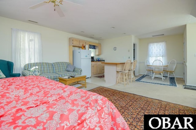 bedroom featuring light carpet, ceiling fan, visible vents, and freestanding refrigerator