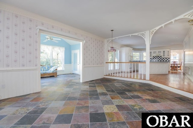 unfurnished room featuring wainscoting, plenty of natural light, and wallpapered walls