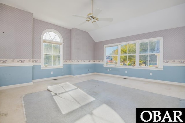 empty room featuring wallpapered walls, baseboards, light colored carpet, ceiling fan, and vaulted ceiling