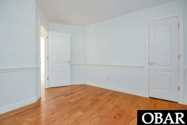 spare room featuring light wood-type flooring and baseboards