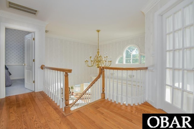 hallway with visible vents, an upstairs landing, wood finished floors, a chandelier, and wallpapered walls