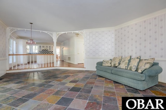 living area featuring a wainscoted wall, crown molding, stone finish floor, and wallpapered walls