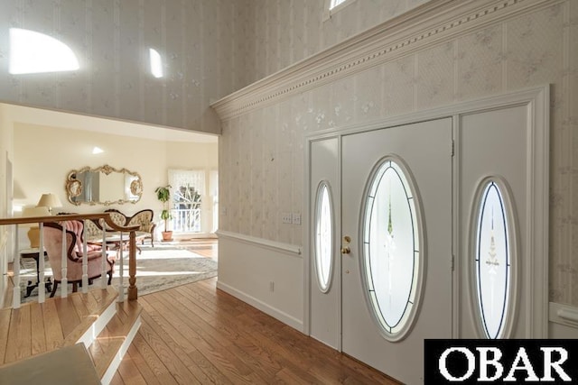 foyer entrance featuring wood finished floors and wallpapered walls