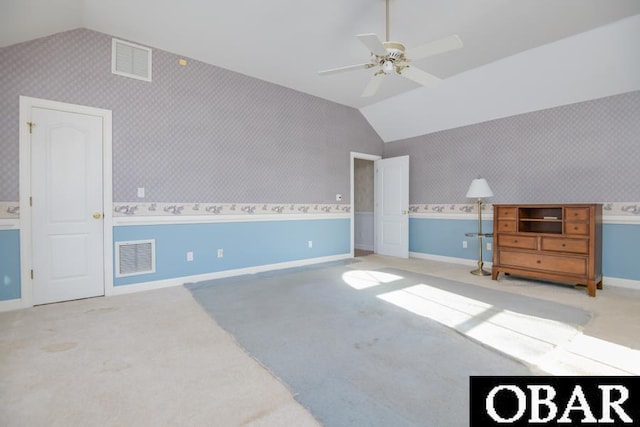 interior space featuring visible vents, vaulted ceiling, and wallpapered walls