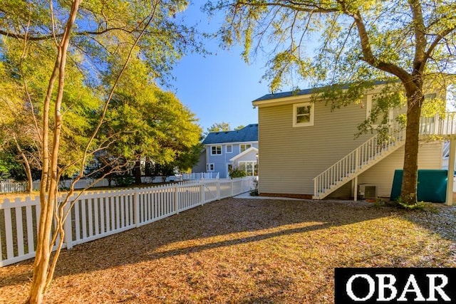 view of yard featuring a fenced backyard, stairway, and cooling unit