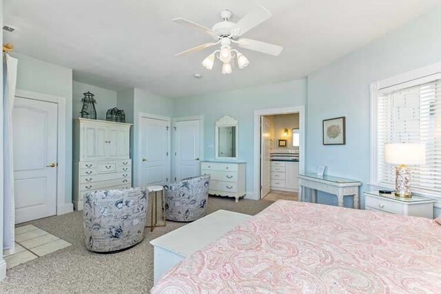 bedroom featuring light carpet, connected bathroom, and ceiling fan